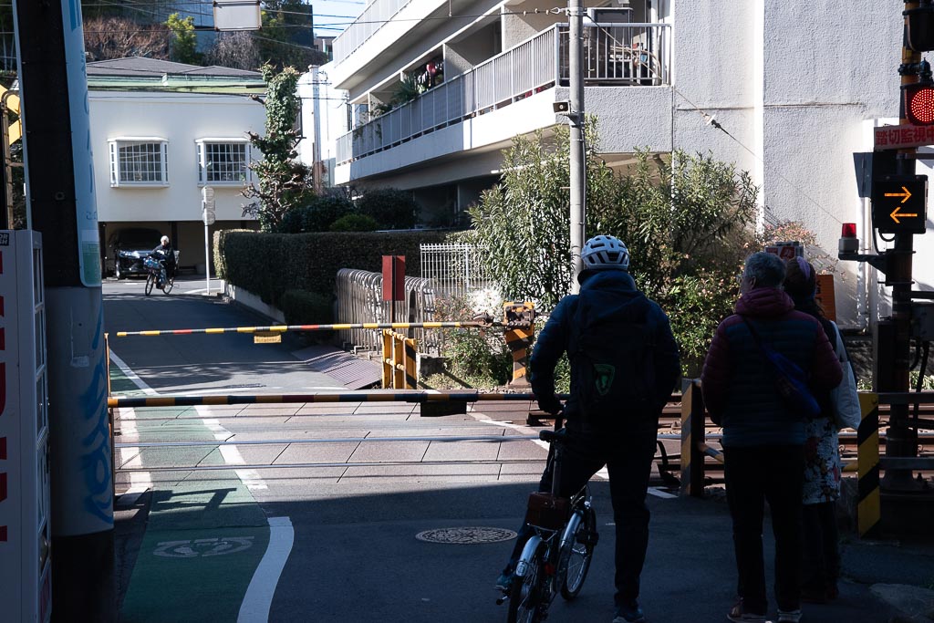 Waiting for the train to pass, which is common in Tokyo but not in other cities.